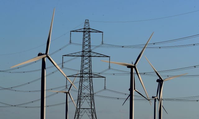 A general view of an electricity pylon with wind turbines in the distance