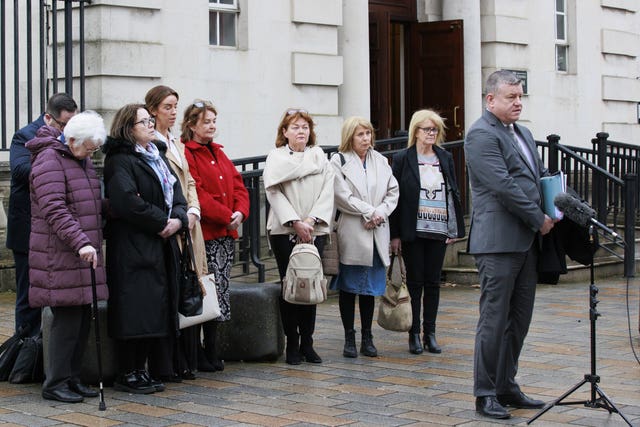 A man stands at a microphone with a group of people behind him