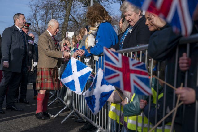 King shaking hands with well-wishers, with Scottish and UK flags in view