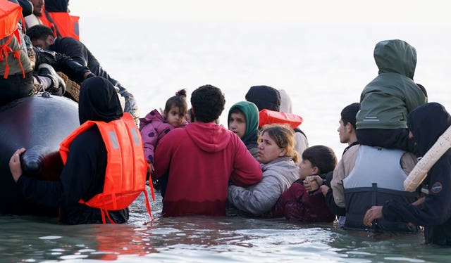 A woman and child try to scramble onboard a small boat leaving the beach at Gravelines