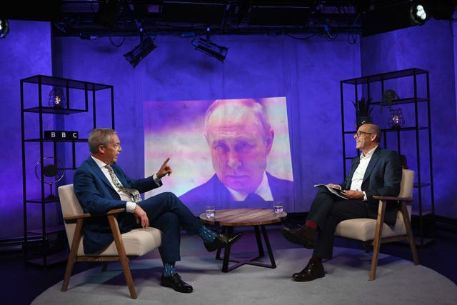 An image of Vladimir Putin is projected onto studio walls as Nigel Farage and Nick Robinson discuss