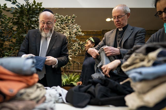 Chief Rabbi Ephraim Mirvis and Archbishop of Canterbury Justin Welby help sort clothing