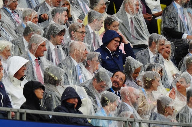 Spectators including Prime Minister Sir Keir Starmer take shelter from the rain