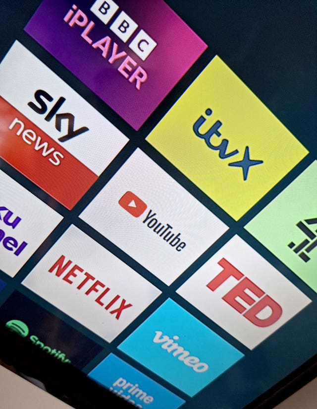 A number of streaming services display on a TV screen