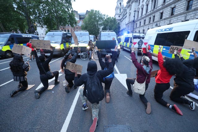 Protesters take a knee in front of police vans during a Black Lives Matter protest rally in Parliament Square 