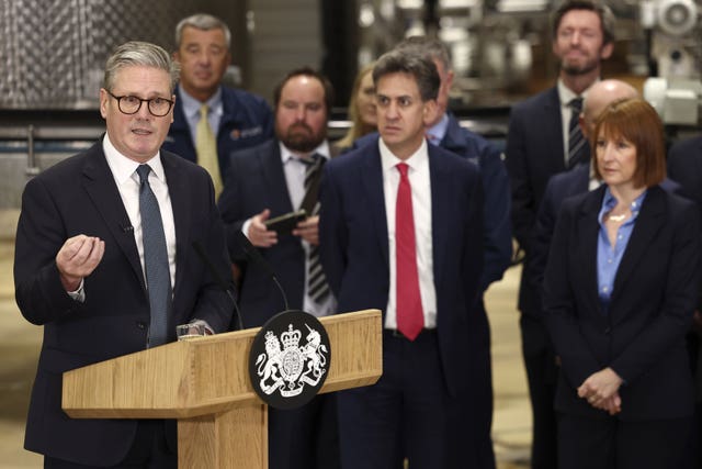 Sir Keir Starmer speaking at a lectern alongside Ed Miliband and Rachel Reeves