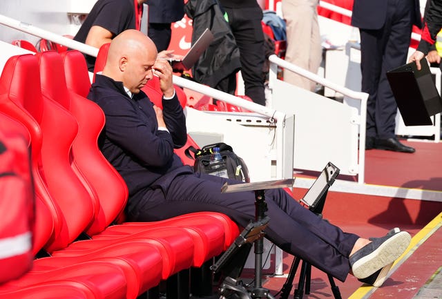 Liverpool head coach Arne Slot sits in the dugout resting his head on his hand