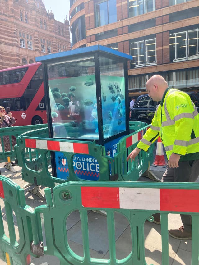 Banksy artwork of a school of fish on a police sentry box with barriers around it