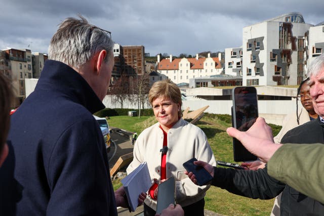 Nicola Sturgeon being questioned by members of the media, with Holyrood behind her