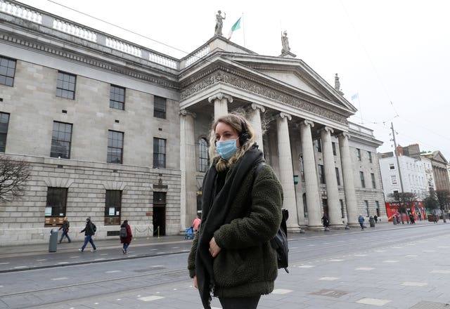 A woman wearing a face mask walks past the GPO on a very quiet O’Connell Street in Dublin’s city centre