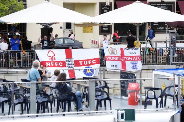 England fans on Friedrichstrasse drape flags next to the river Spree in Berlin