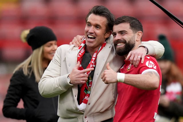 Wrexham co-chairman Rob McElhenney and forward Elliot Lee celebrate on the pitch after a League Two match against Stockport