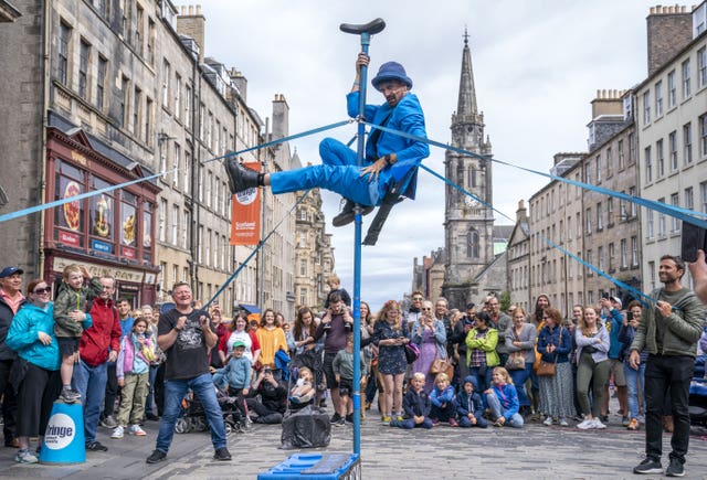 Performer dressed in blue in front of onlookers on the Royal Mile