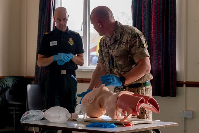 A soldier from the Royal Signals being mentored by an NHS representative in dealing with airways