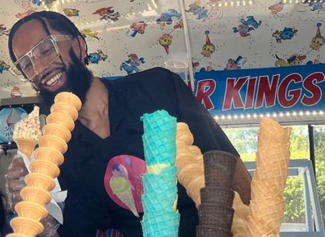 Shazad Khan standing behind some ice cream cones and holding an ice cream