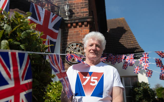 Man wearing VE Day 75 t-shirt outside his home covered in Union Jack flags and bunting