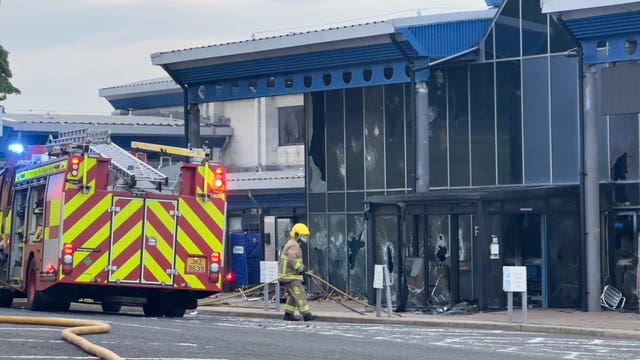 Firefighters outside a glass-fronted building which has been vandalised