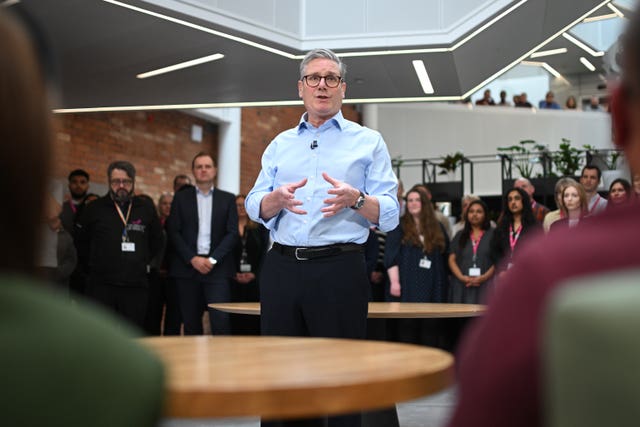 Sir Keir Starmer gesturing with his hands while delivering a speech, with his audience in front of and behind him