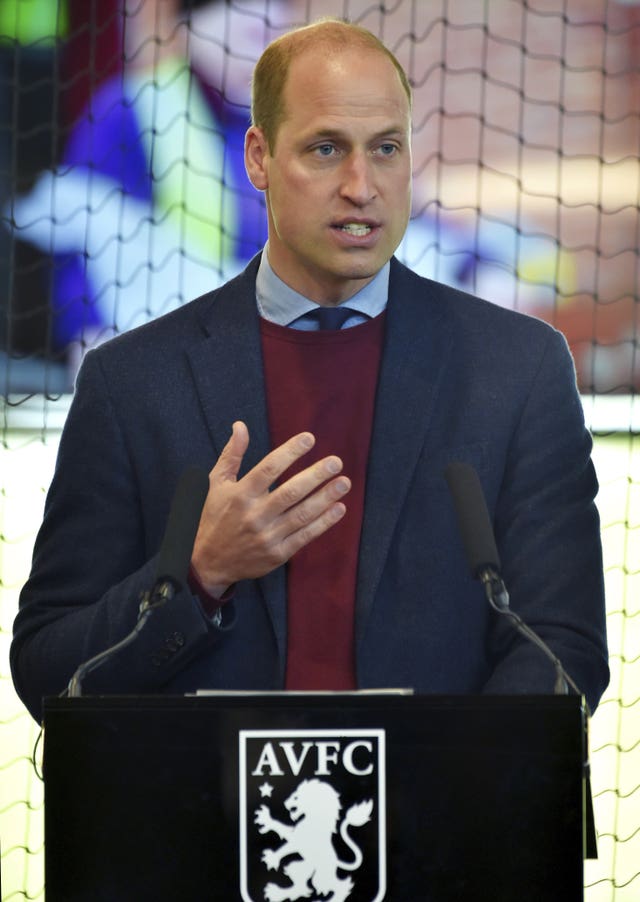 The Prince of Wales standing at a lectern that shows the Aston Villa crest