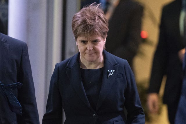 Nicola Sturgeon with her head down as she walks along a street