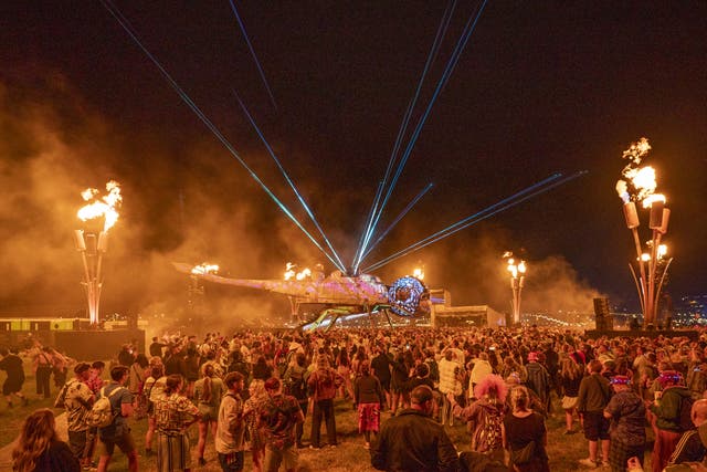 People watch lasers coming from a dragonfly sculpture at Glastonbury Festival 2025