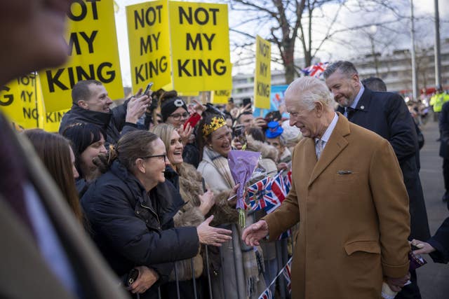 Anti-monarchy protesters waving placards reading 