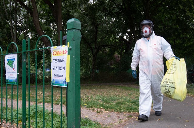 A worker for Leicester City Council carries a bag of clinical waste away from a Covid-19 testing station at Spinney Hill Park in Leicester (Joe Giddens/PA)