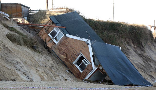 A house collapsed following a tidal surge which eroded the cliff edge on Hemsby beach in Norfolk in 2013 (Chris Radburn/PA)