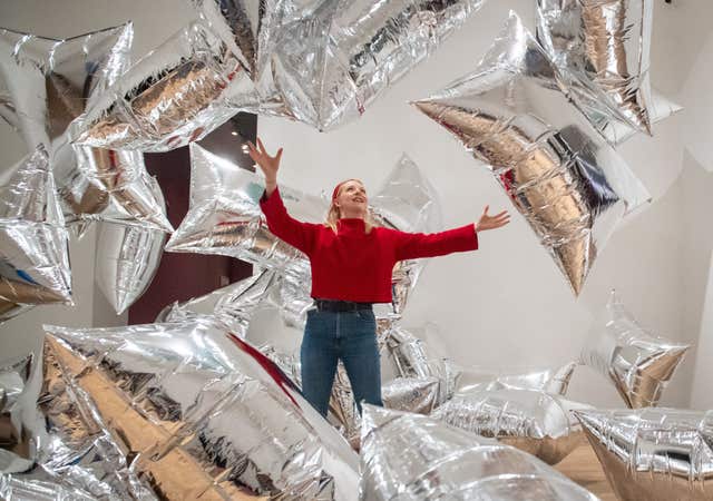 A Tate Modern gallery assistant interacts with the Silver Clouds installation at Tate Modern