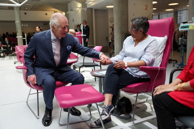 The King holds hands with patient Asha Millan at University College Hospital Macmillan Cancer Centre in April 