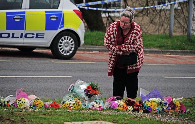 A woman lays flowers on Sheepstor Road in Plymouth