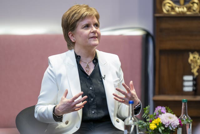 Nicola Sturgeon speaking with hands raised while sitting on a stage