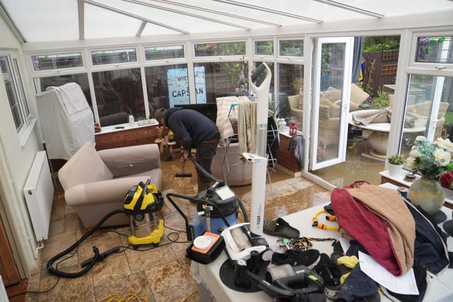 Neighbours help to clear flood water from the home of Jon Sayles in Grendon, Northamptonshire