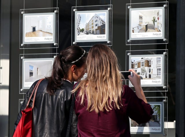 Two people looking in the window of an estate agent