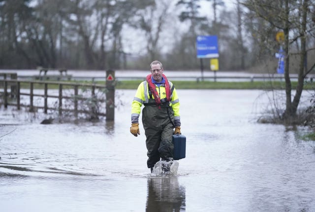 A Canal & River Trust worker walks through floodwater at Naburn Lock on the outskirts of York 