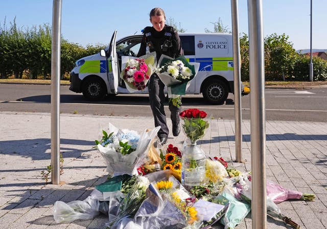 A police officer leaves flowers at the Cleveland Police HQ Memorial Garden in Middlesbrough 