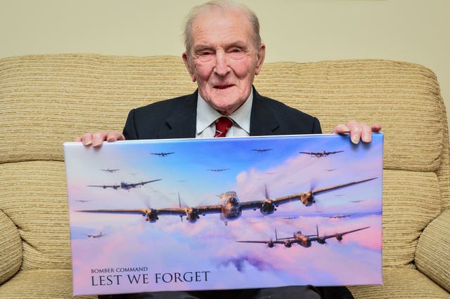 Johnson photographed in 2017 at his home in Bristol holding a picture of Lancaster bombers (Ben Birchall/PA)