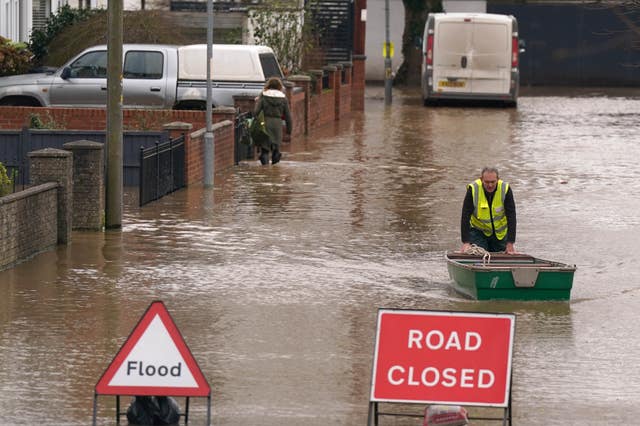 A flood warden pushes a boat in floodwater