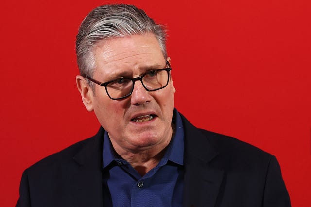 Head and shoulders photo of Sir Keir Starmer speaking, in front of a red screen