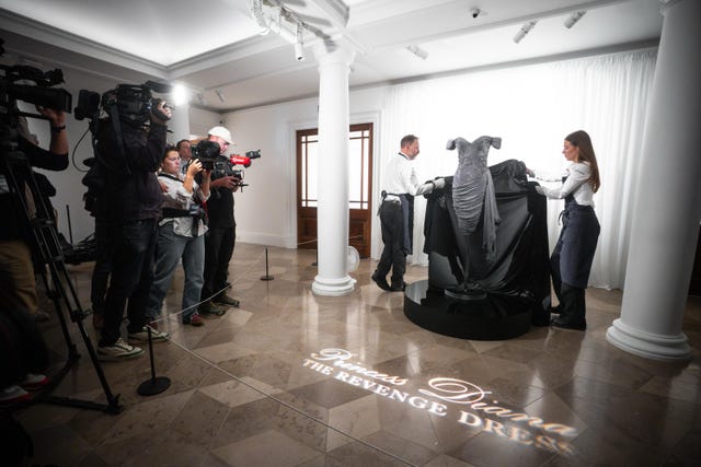 Auction house staff unveil Diana, Princess of Wales's 'revenge dress' during a preview at Sotheby’s in central London of Diana, Princess of Wales’s black silk Christina Stambolian dress which was worn during a Vanity Fair fundraising dinner at the Serpentine Gallery in London in 1994, on the same night her then-husband the Prince of Wales publicly admitted his infidelity on national television