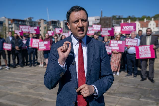 Anas Sarwar speaking in front of a large group of Scottish Labour supporters, holding placards
