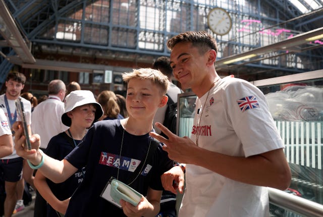 Triathlon champion Alex Yee poses for a picture with a fan 