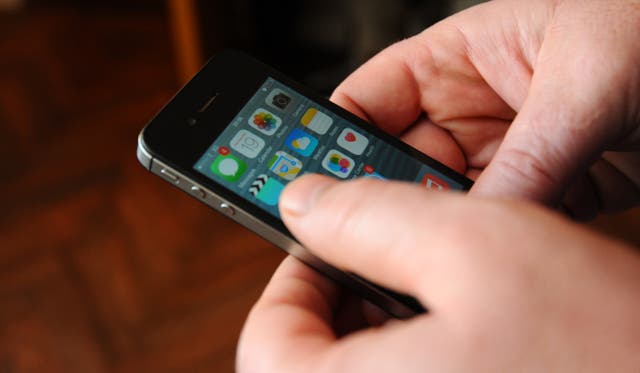 A man using an Apple iPhone 4s with iOS 8.1 software