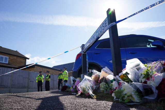 Police officers, police tape and floral tributes in Ashlyn Close