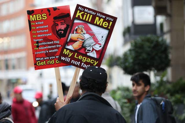 A man holds posters denouncing Saudi Crown Prince Mohammed bin Salman and hailing killed journalist Jamal Khashoggi in London