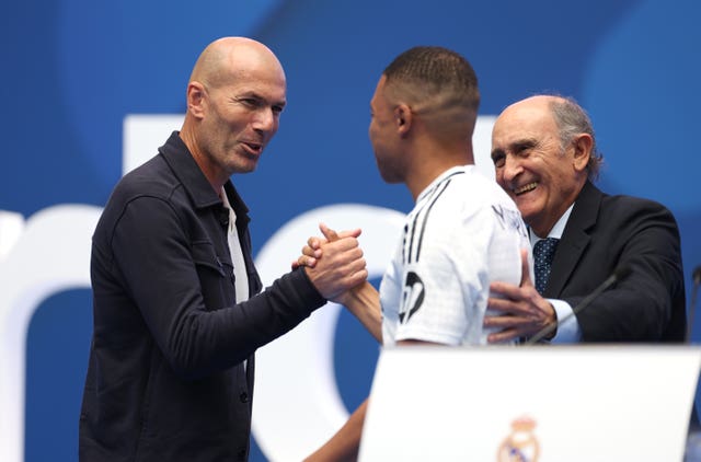 Kylian Mbappe, right, clasps hands with Zinedine Zidane