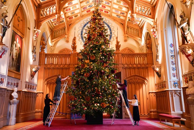 Royal Collection Trust staff using ladders to decorate a Christmas treet in St George’s Hall, Windsor Castle