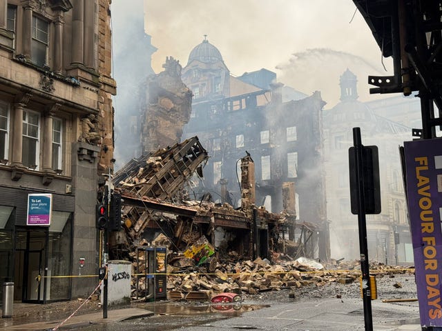 View of a collapsed building, with smoke rising around it