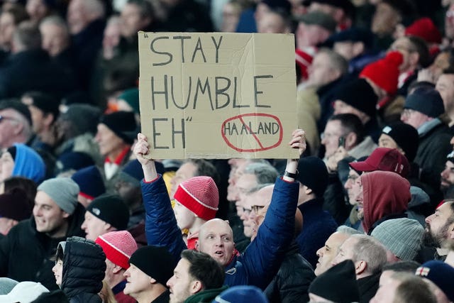 An Arsenal fan holds a sign referencing Manchester City’s Erling Haaland's humble quote