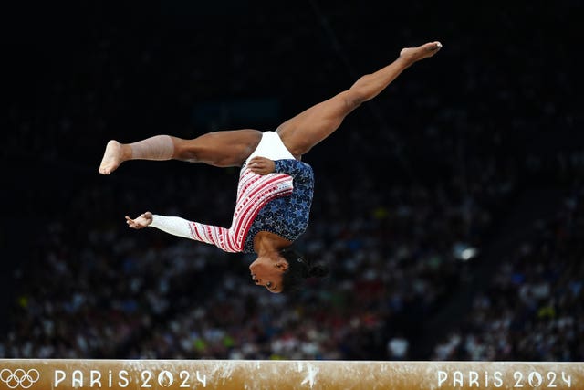 Simone Biles performs during the artistic gymnastics on the beam - jumping upside down facing the floor. 